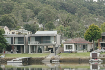 Waterfront properties with calm water in the foreground and trees in the background.