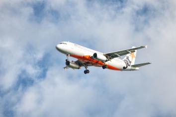A commercial airline plane taking off against a partly cloudy sky